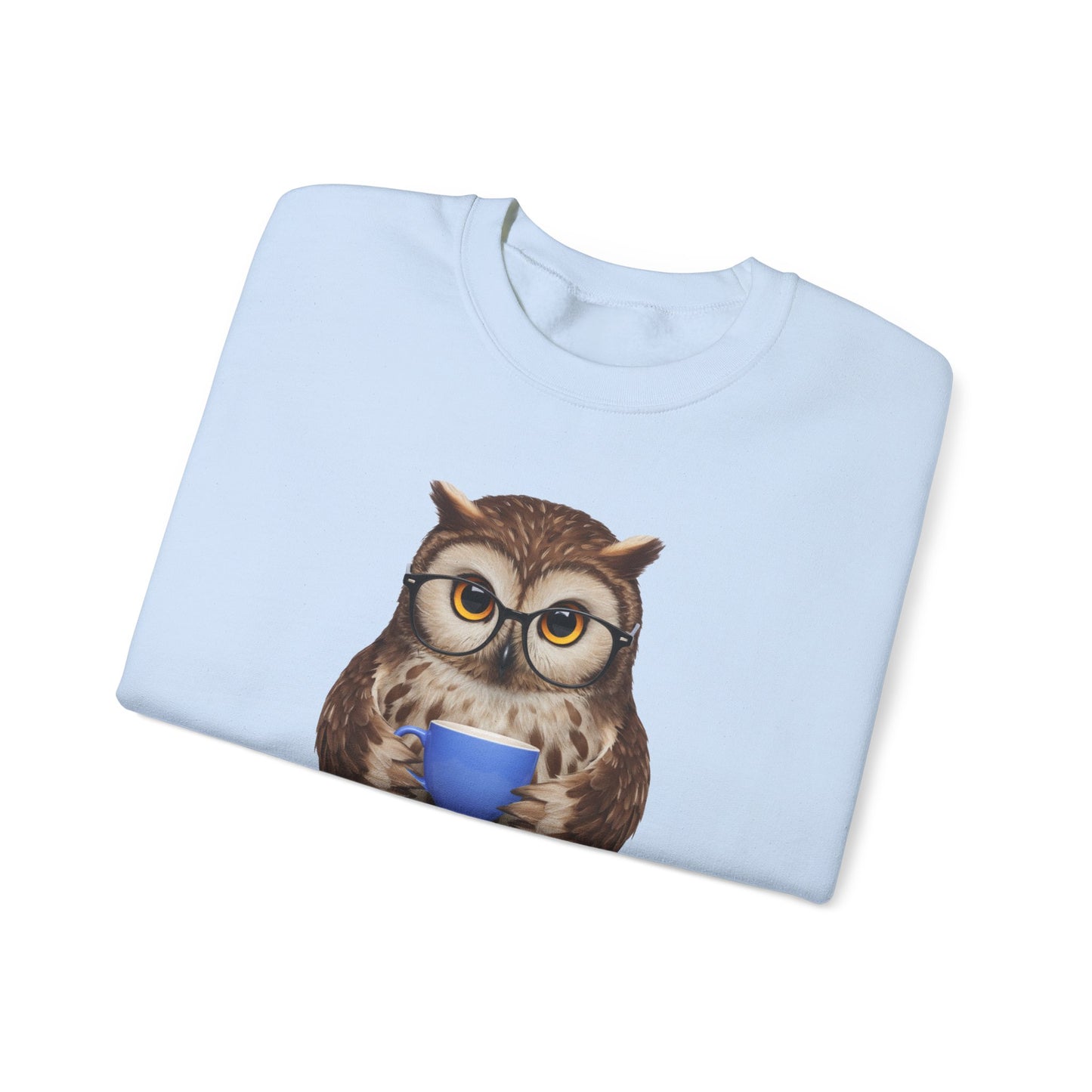 Folded light blue sweatshirt with an owl design holding a blue mug on a white background