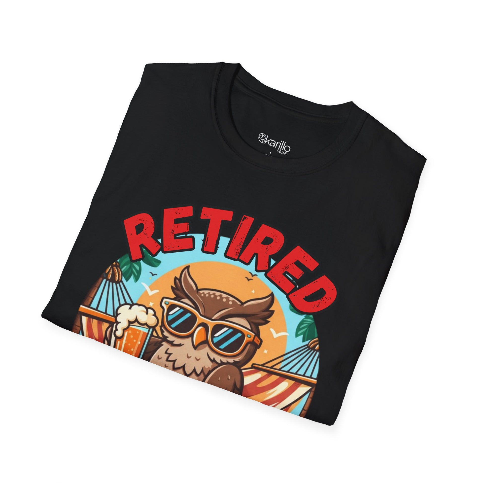 Folded black t-shirt with 'Retired' design featuring an owl, sunglasses, and beach elements on a white background.