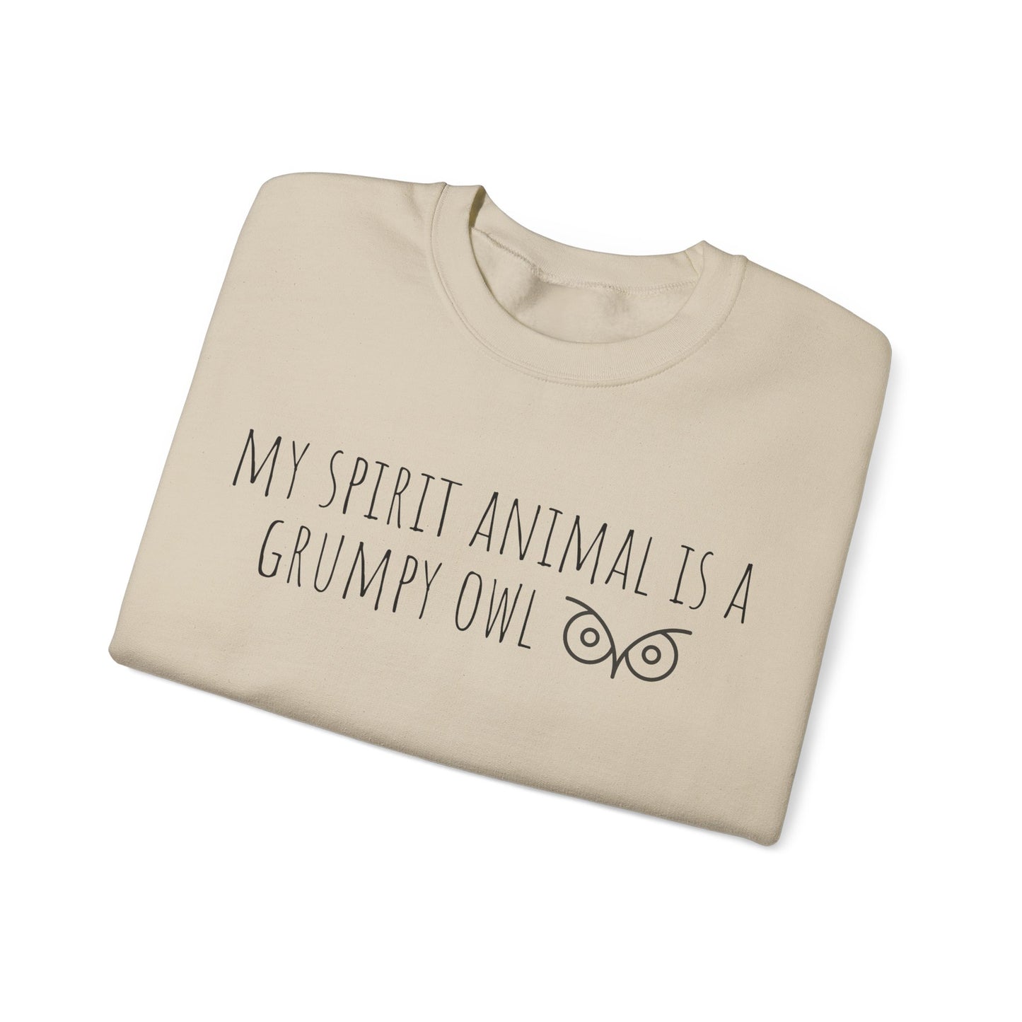 Folded beige sweatshirt with text 'My spirit animal is a grumpy owl' on a white background