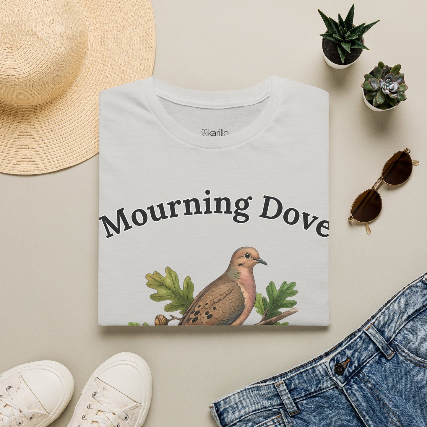 Folded White t-shirt with a mourning dove graphic and 'Mourning Dove' text on a white background