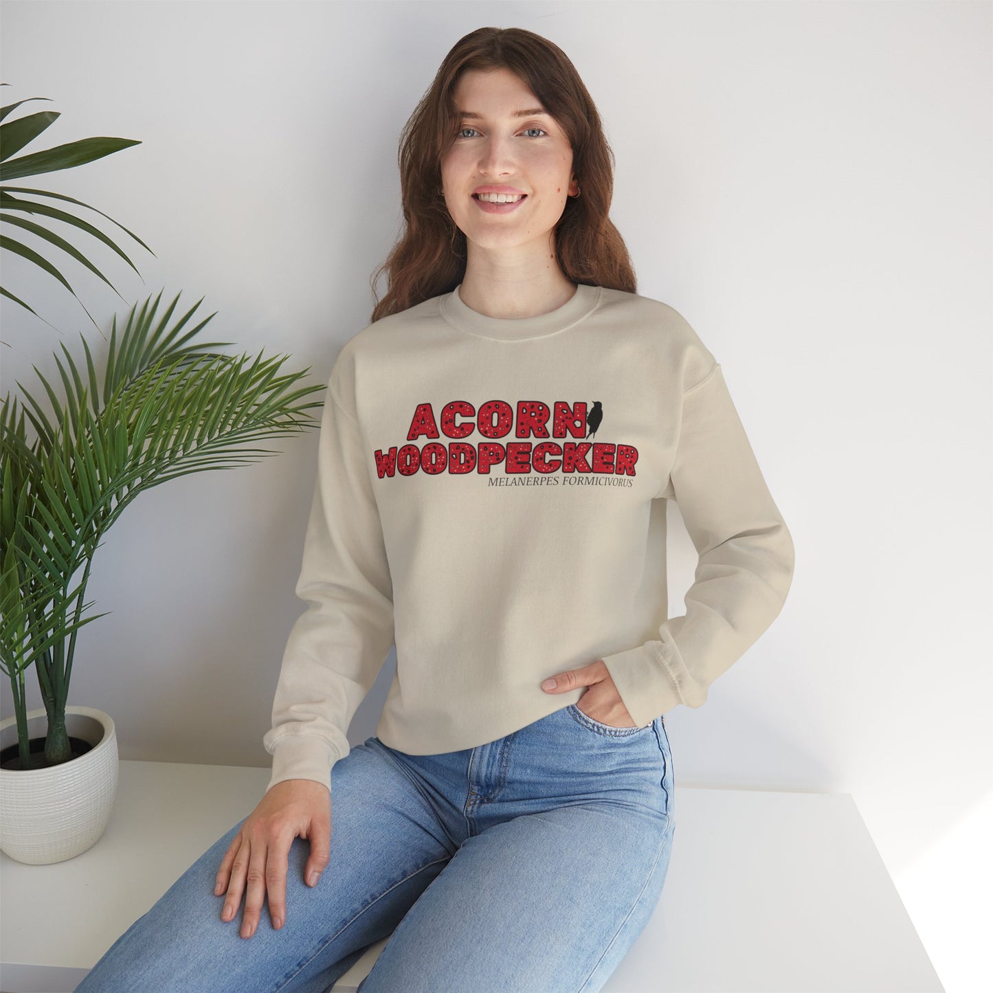 Person wearing beige sweatshirt with 'Acorn Woodpecker' text and logo on a white background