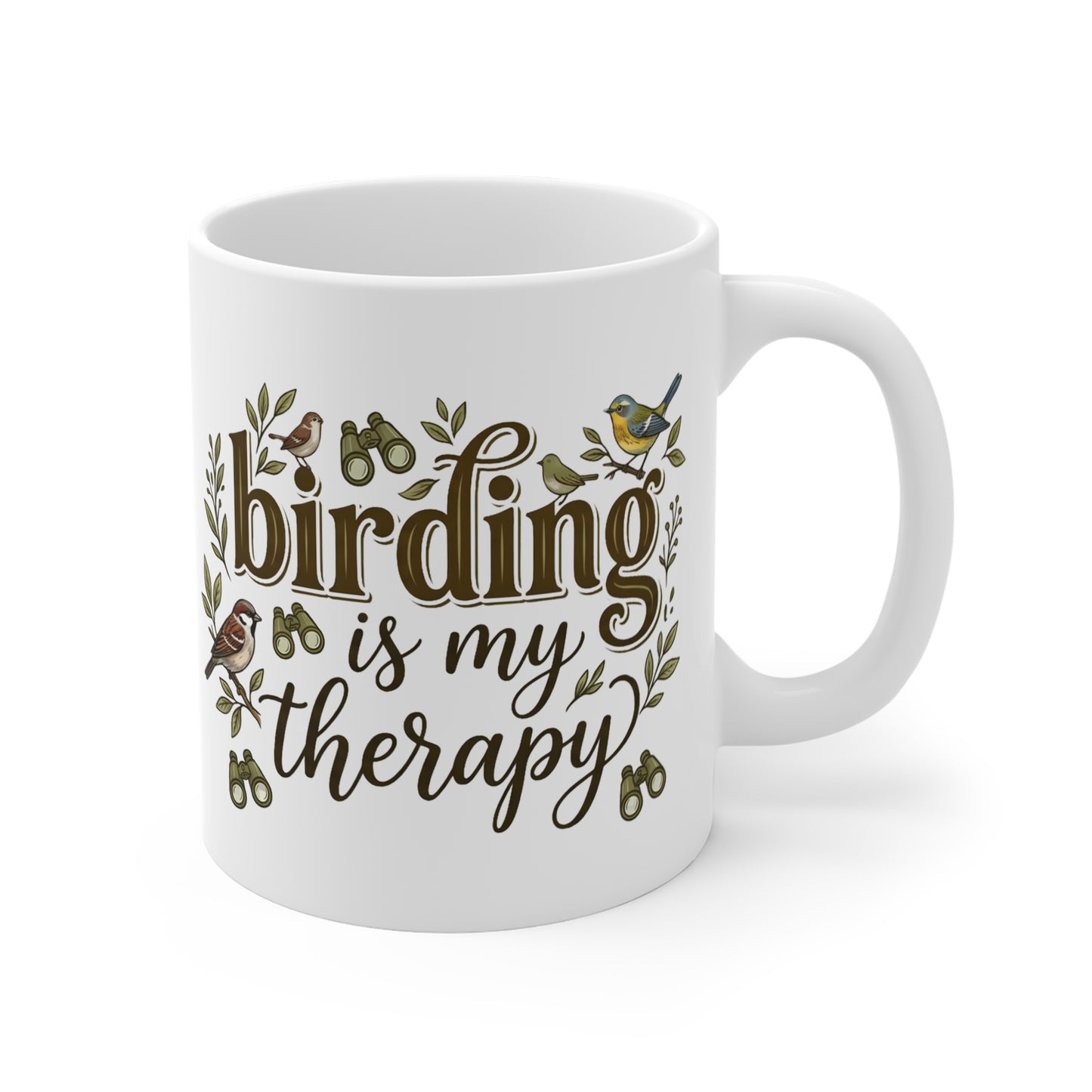 A white ceramic coffee mug with a handle, featuring the phrase 'birding is my therapy' in brown script and serif fonts, decorated with small bird illustrations and green leaves.