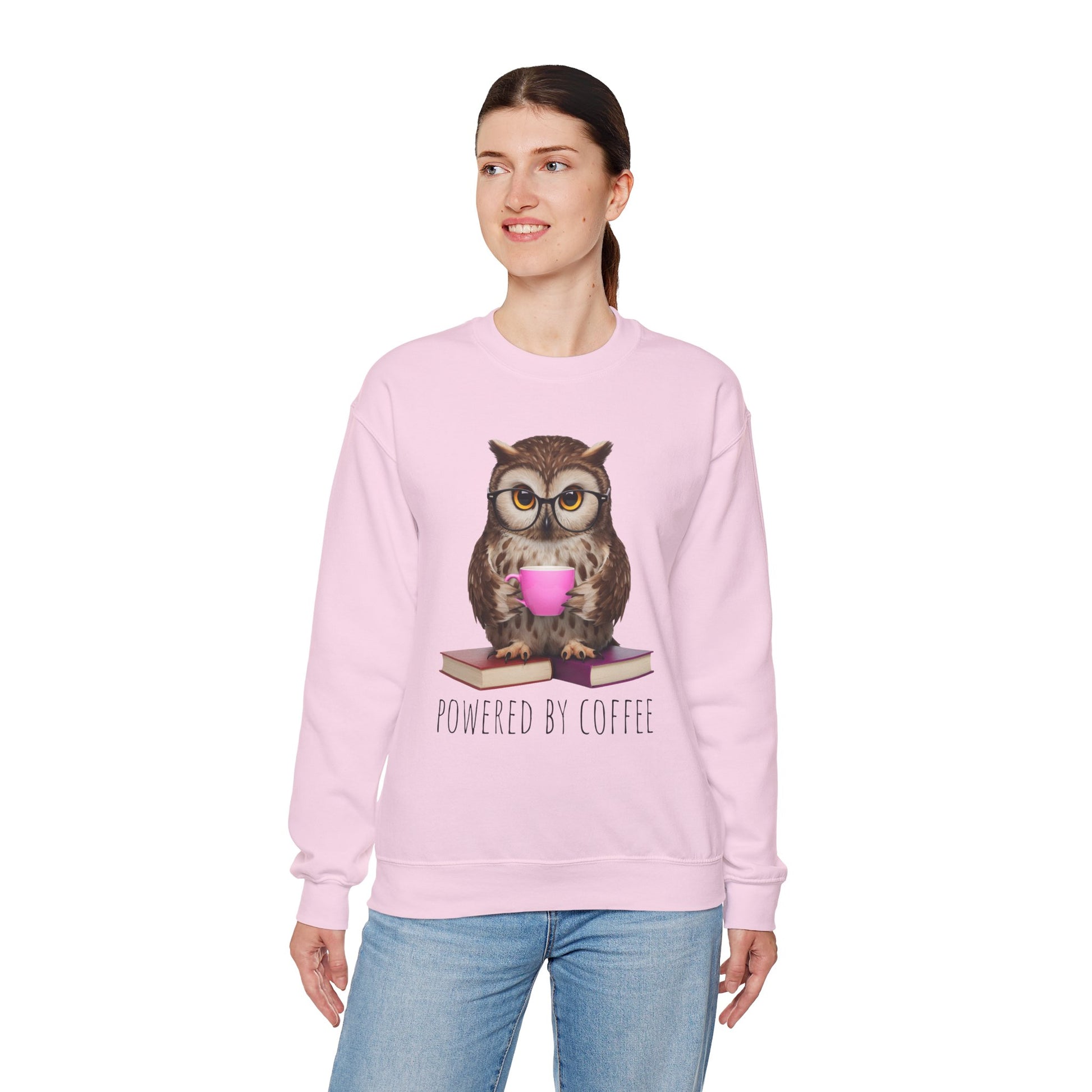 Person wearing a pink sweatshirt with an owl graphic and 'Powered by Coffee' text on a white background