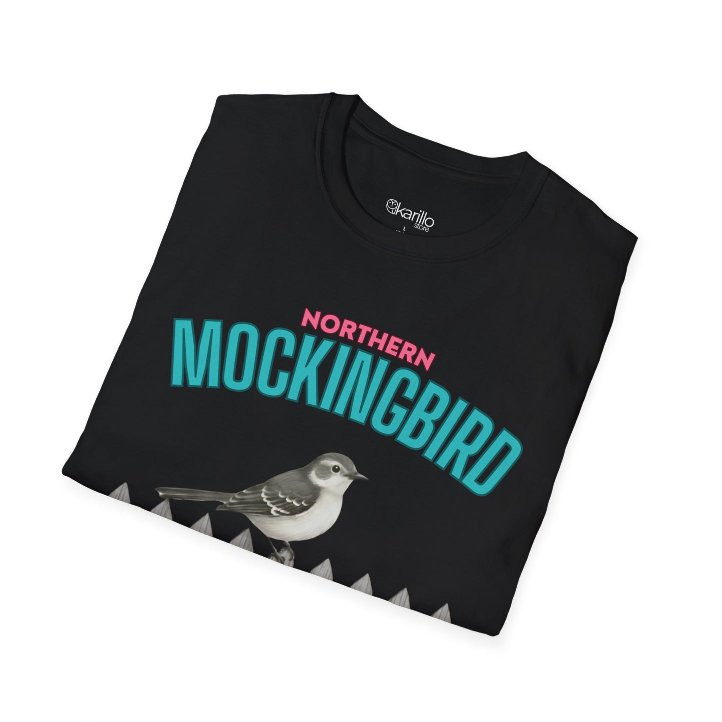 A folded black t-shirt with a graphic print featuring the text 'NORTHERN MOCKINGBIRD' in teal and pink, an illustration of a mockingbird perched on a white picket fence with green foliage, with white background.